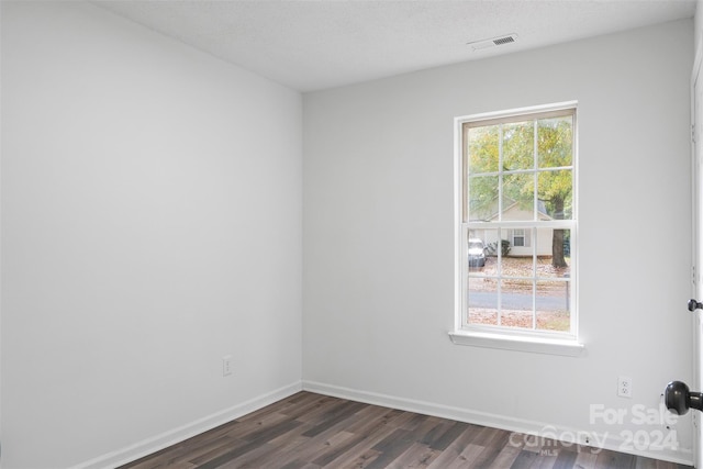 spare room featuring dark wood-type flooring and a textured ceiling