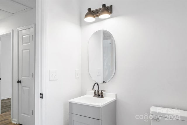 bathroom with wood-type flooring, vanity, and toilet