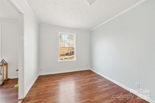 empty room featuring dark hardwood / wood-style floors, ornamental molding, and a textured ceiling