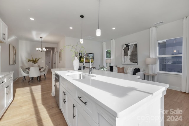 kitchen featuring pendant lighting, a center island with sink, sink, light hardwood / wood-style floors, and white cabinetry