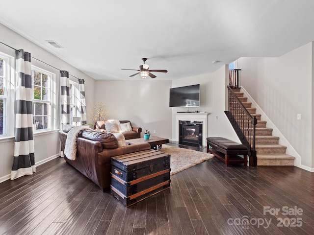 living room featuring stairs, dark wood-style flooring, visible vents, and baseboards