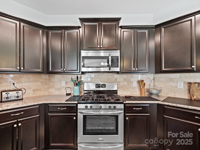 kitchen with stainless steel appliances, light stone counters, backsplash, and dark brown cabinetry