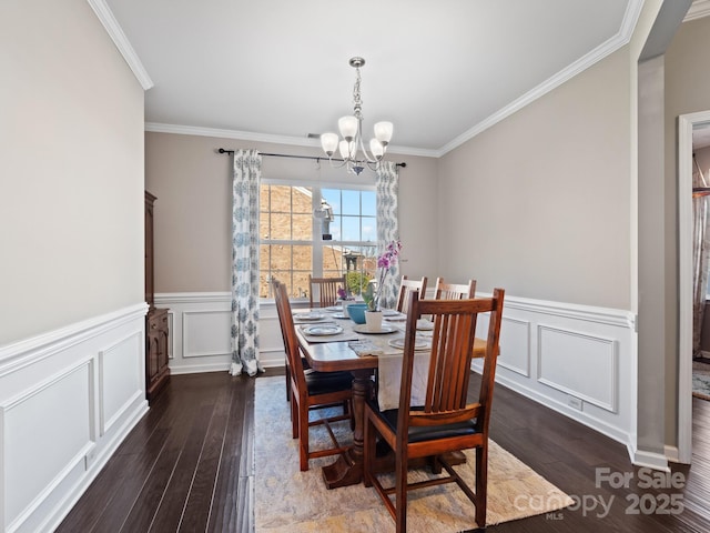 dining area with an inviting chandelier, crown molding, a decorative wall, and wood finished floors