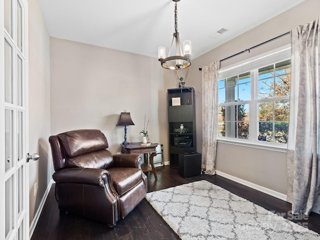 living area with dark wood-style floors, baseboards, and a chandelier