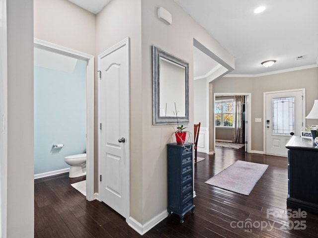 hall featuring crown molding, baseboards, and dark wood-type flooring