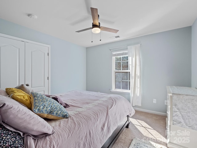 bedroom featuring light carpet, a ceiling fan, visible vents, baseboards, and a closet