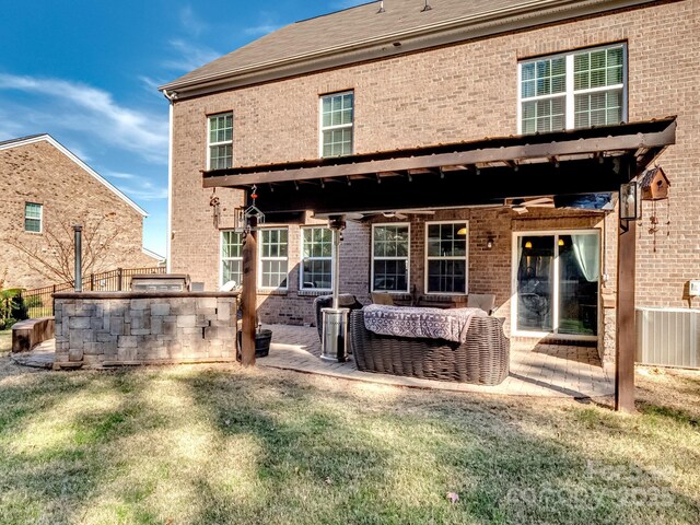 rear view of house featuring a patio area, brick siding, a yard, and fence