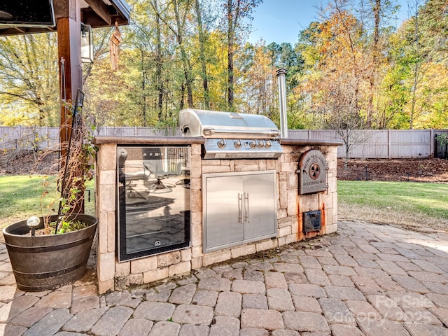 view of patio / terrace featuring a grill, fence, and an outdoor kitchen