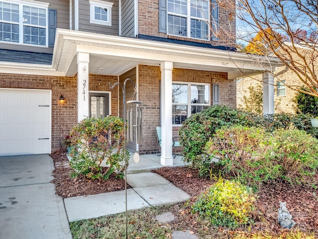 property entrance featuring a porch, brick siding, and a garage