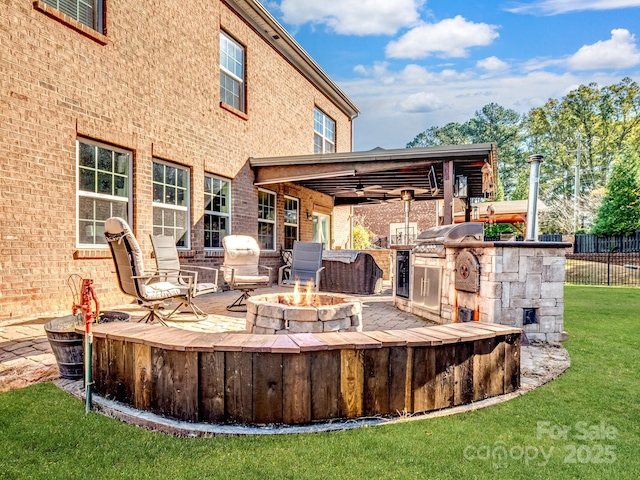 view of patio featuring an outdoor fire pit, a grill, an outdoor kitchen, and fence