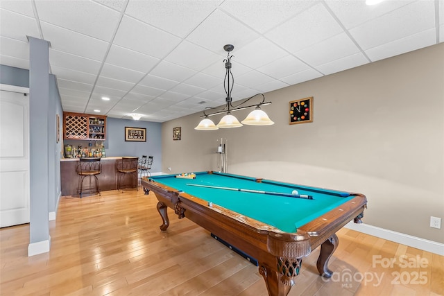 recreation room featuring baseboards, a drop ceiling, wood finished floors, pool table, and bar area