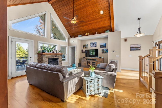 living area featuring baseboards, stairway, light wood-style floors, a fireplace, and high vaulted ceiling