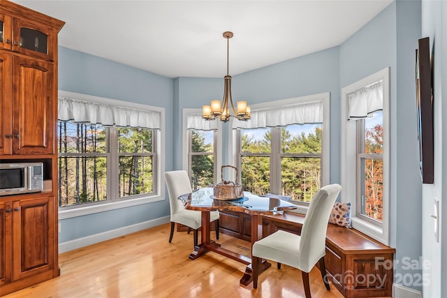 dining room with a chandelier, baseboards, and light wood-style floors