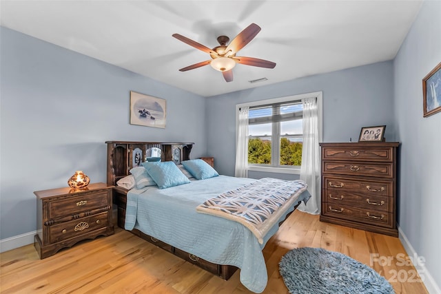 bedroom featuring light wood-style floors, visible vents, ceiling fan, and baseboards