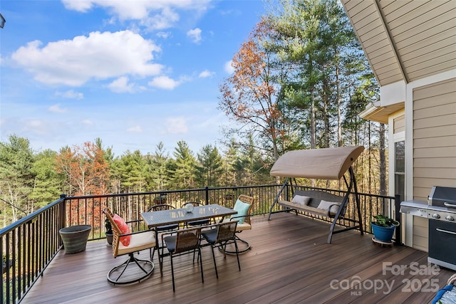 wooden terrace featuring area for grilling and outdoor dining space