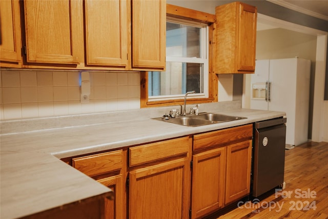 kitchen featuring dishwasher, sink, crown molding, decorative backsplash, and light wood-type flooring