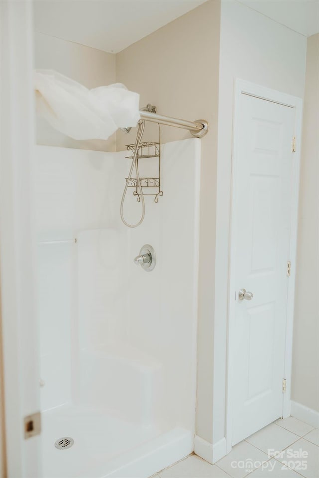 full bath with a stall shower, tile patterned floors, and baseboards