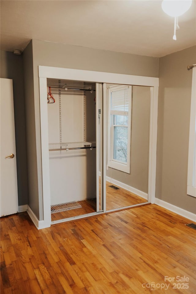 unfurnished bedroom featuring baseboards, visible vents, and wood finished floors