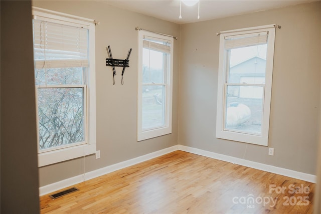 spare room featuring baseboards, visible vents, and wood finished floors