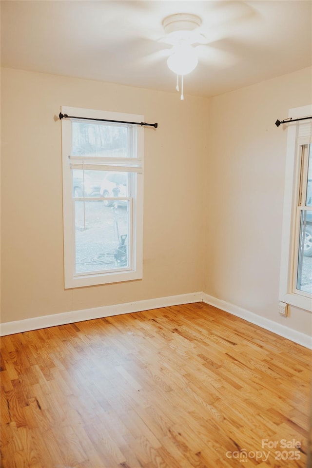 spare room featuring baseboards, a ceiling fan, and light wood-style flooring