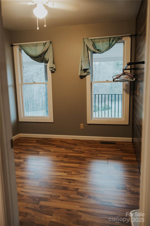 unfurnished room with visible vents, ceiling fan, wood finished floors, and baseboards