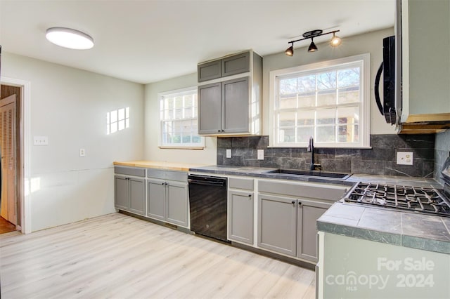 kitchen featuring backsplash, gray cabinetry, sink, dishwasher, and light hardwood / wood-style floors