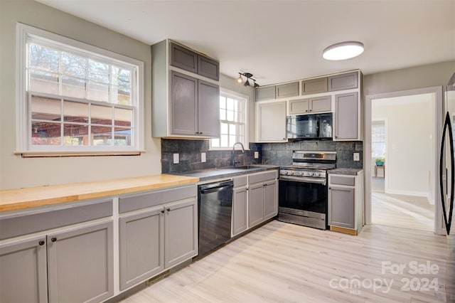 kitchen featuring decorative backsplash, plenty of natural light, black appliances, and sink