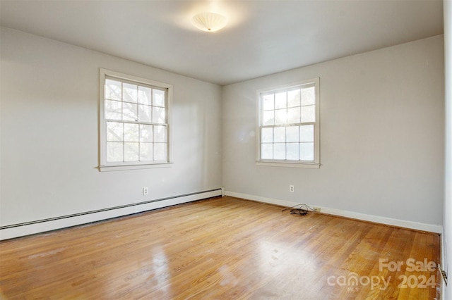 spare room with a baseboard heating unit and light wood-type flooring