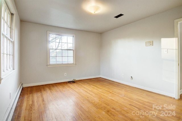 unfurnished room with hardwood / wood-style floors and a baseboard radiator