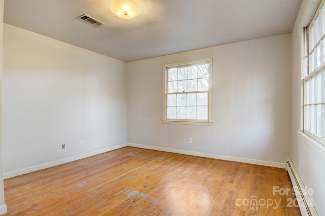 unfurnished room featuring a baseboard radiator and light wood-type flooring