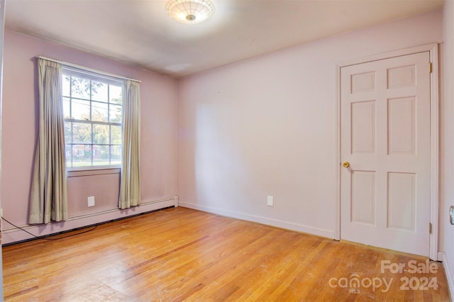 spare room featuring a baseboard radiator and light hardwood / wood-style flooring