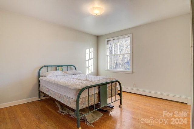 bedroom featuring a baseboard heating unit and hardwood / wood-style flooring