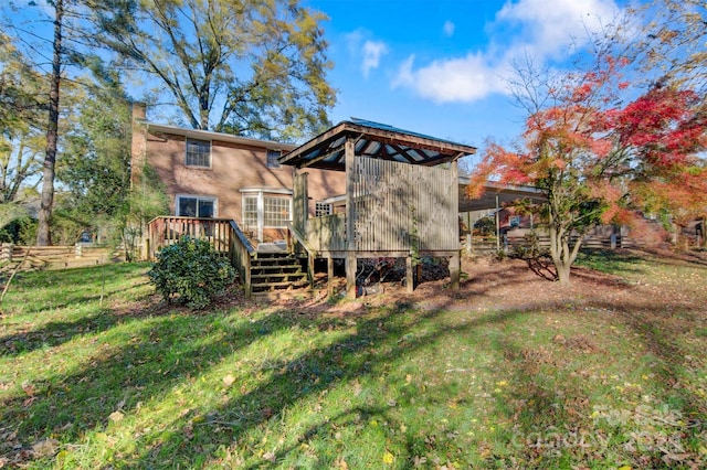 back of property featuring a deck and a lawn