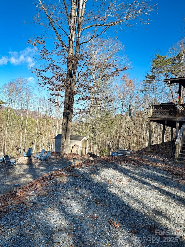 view of yard featuring an outbuilding, a storage shed, a forest view, and stairs