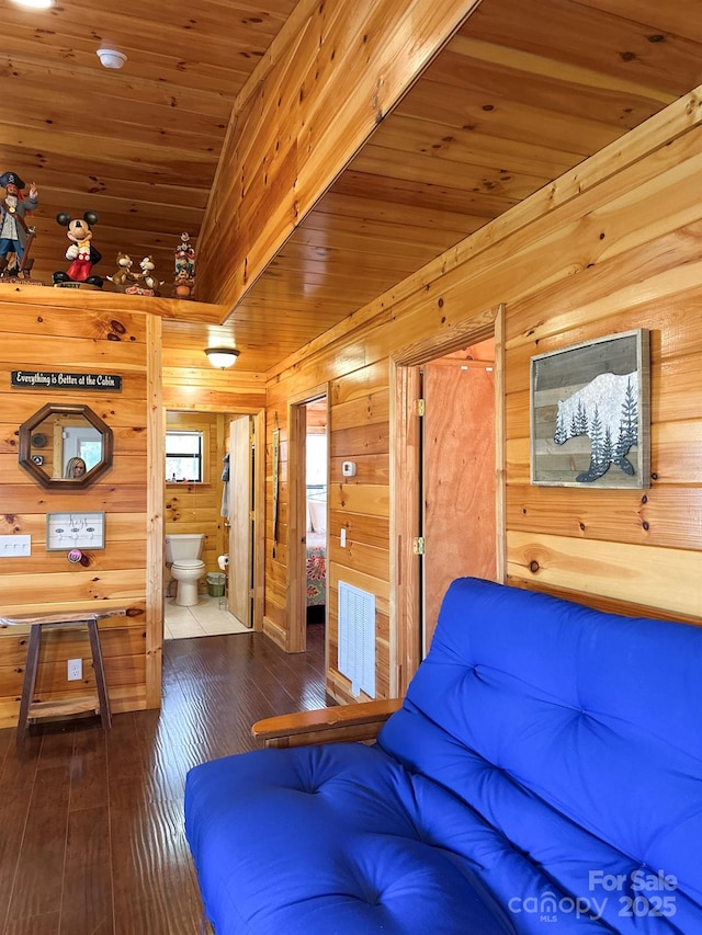 unfurnished living room with wooden walls, wood ceiling, visible vents, and hardwood / wood-style floors