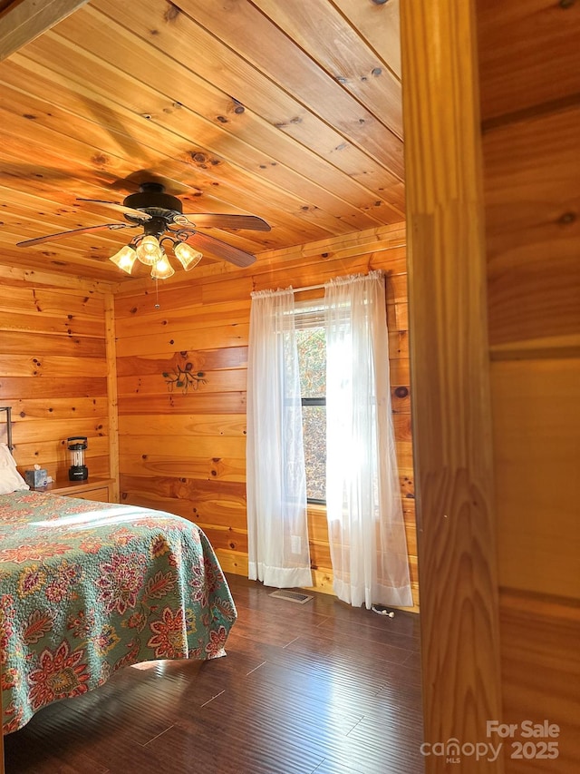 bedroom featuring dark wood-style floors, wooden walls, wood ceiling, and a ceiling fan