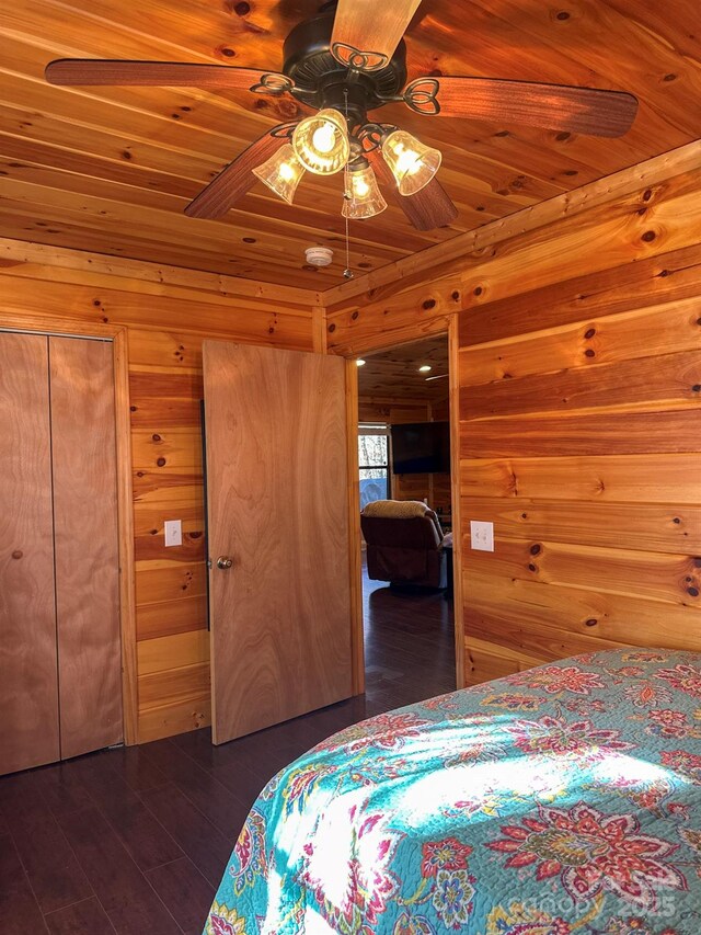 bedroom with ceiling fan, wooden walls, wood ceiling, and dark wood finished floors