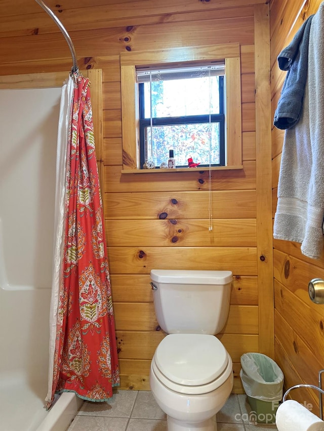 bathroom with tile patterned flooring, toilet, wooden walls, and a shower with curtain