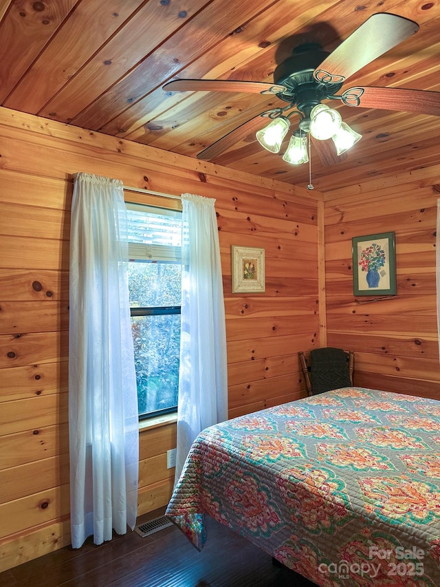 bedroom with wood walls, wood ceiling, a ceiling fan, and wood finished floors