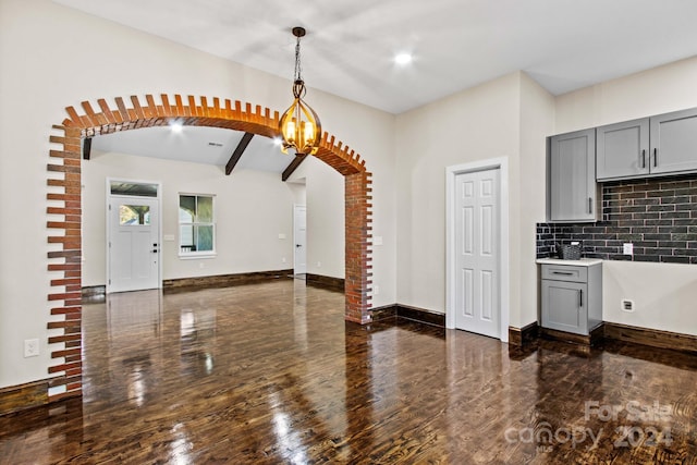 kitchen with dark hardwood / wood-style flooring, an inviting chandelier, tasteful backsplash, gray cabinetry, and pendant lighting