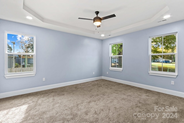 empty room featuring ceiling fan, carpet, and a tray ceiling