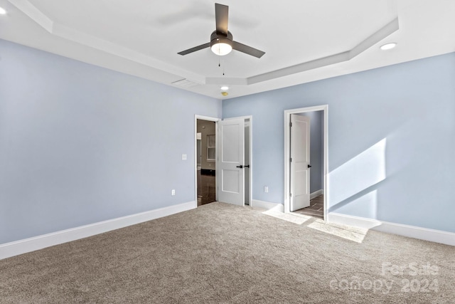 unfurnished bedroom featuring light colored carpet, ceiling fan, and a raised ceiling