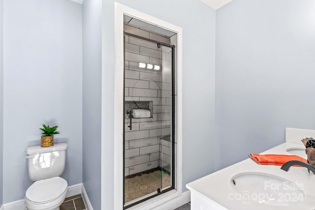 bathroom with tile patterned flooring, vanity, toilet, and a shower with shower door