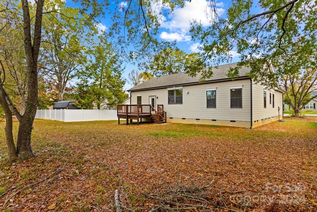 rear view of property featuring a wooden deck and a yard