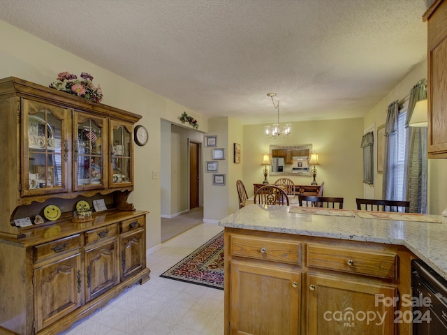 kitchen featuring light stone countertops, a textured ceiling, decorative light fixtures, and an inviting chandelier