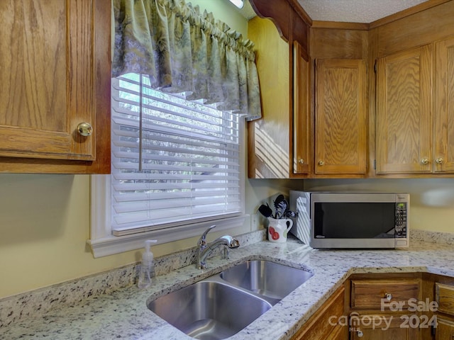 kitchen with light stone countertops, a textured ceiling, and sink