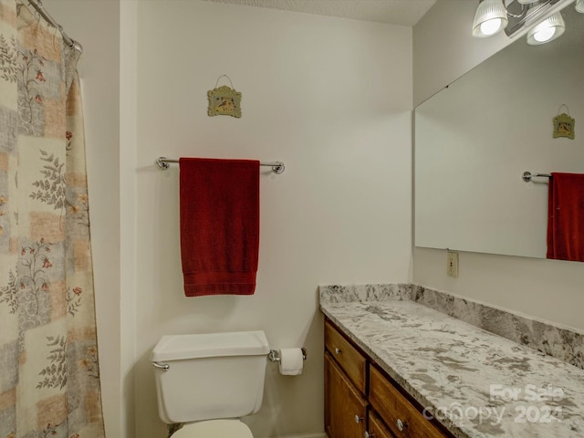 bathroom with a textured ceiling, vanity, and toilet