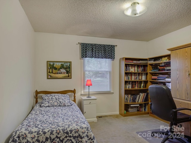 bedroom with light colored carpet and a textured ceiling