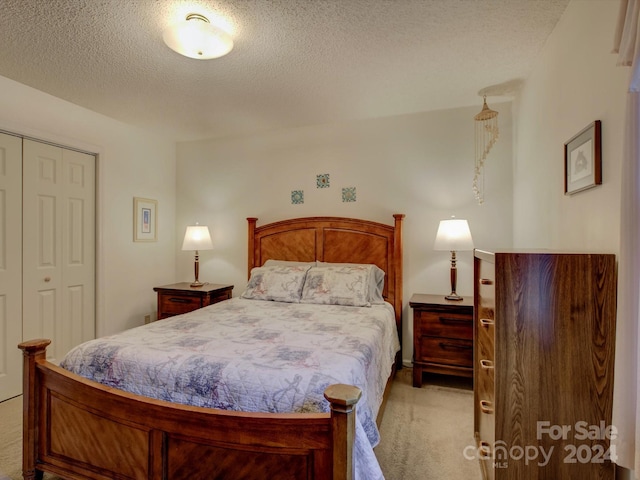 carpeted bedroom featuring a textured ceiling and a closet