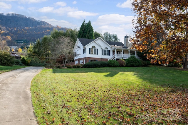 view of front of home featuring a mountain view, covered porch, and a front yard